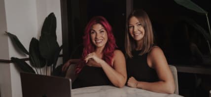 Two women sitting at a table smiling.