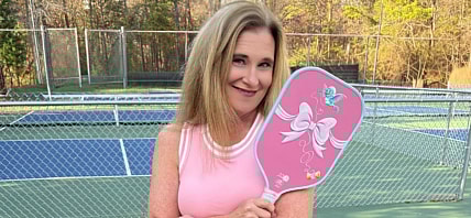 Woman wearing pink and holding a pickleball racket.