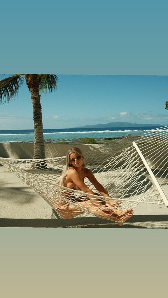 Emily Elizabeth sitting on a hammock at the beach.