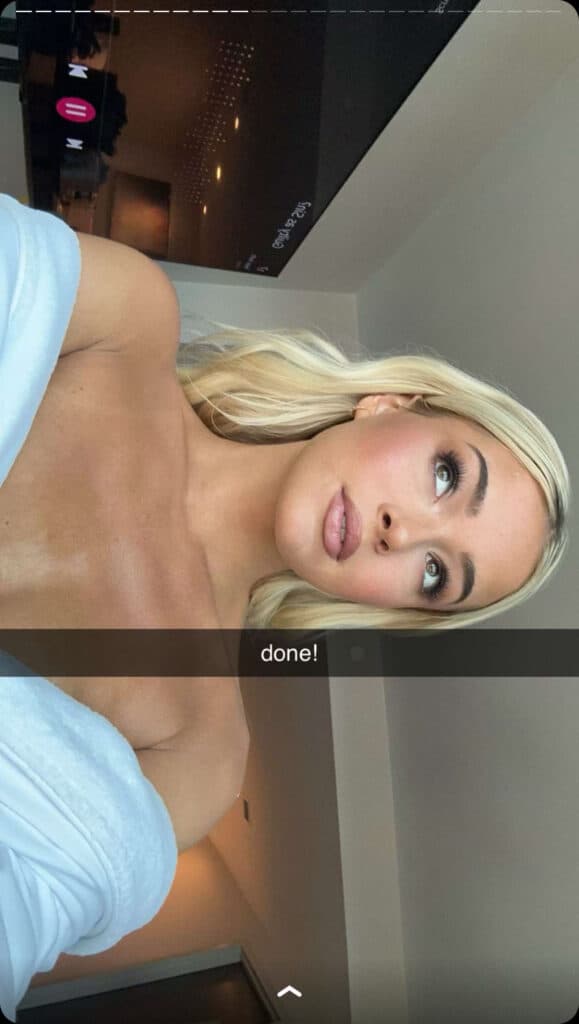 Olivia Dunne takes a selfie while wearing a white robe.