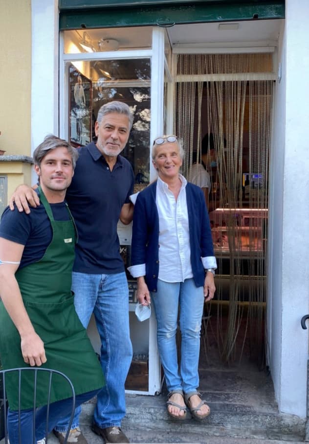 George Clooney posing with two other people outside a storefront