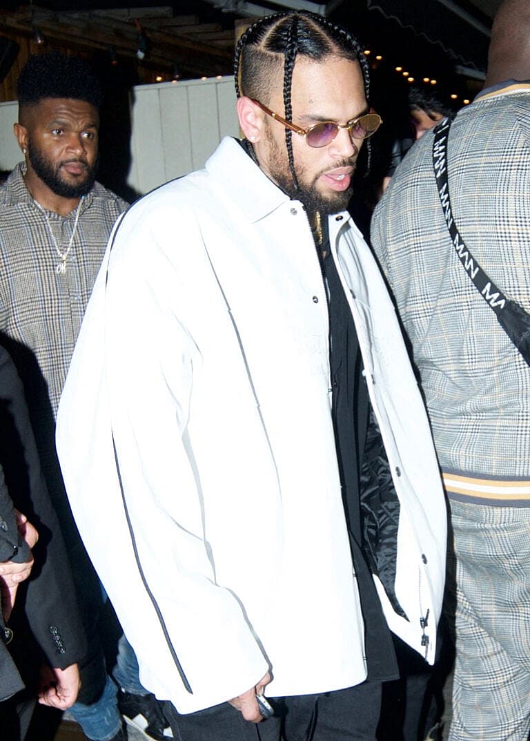 Chris Brown outside in a reflective jacket with braids.