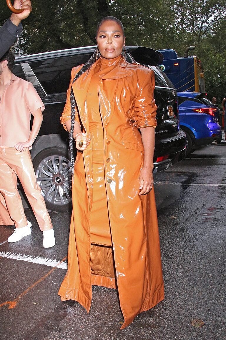Janet Jackson in orange patent trench coat arriving at event