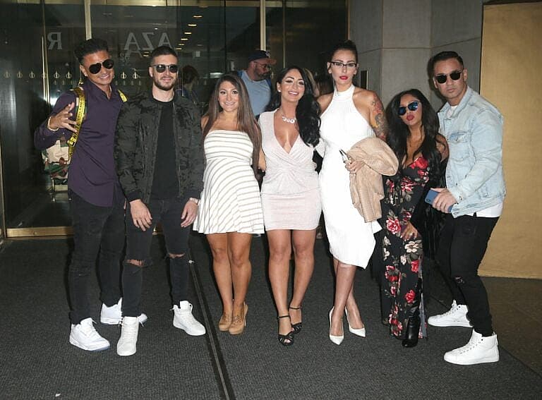 Group of eight people posing together indoors at what appears to be a media event