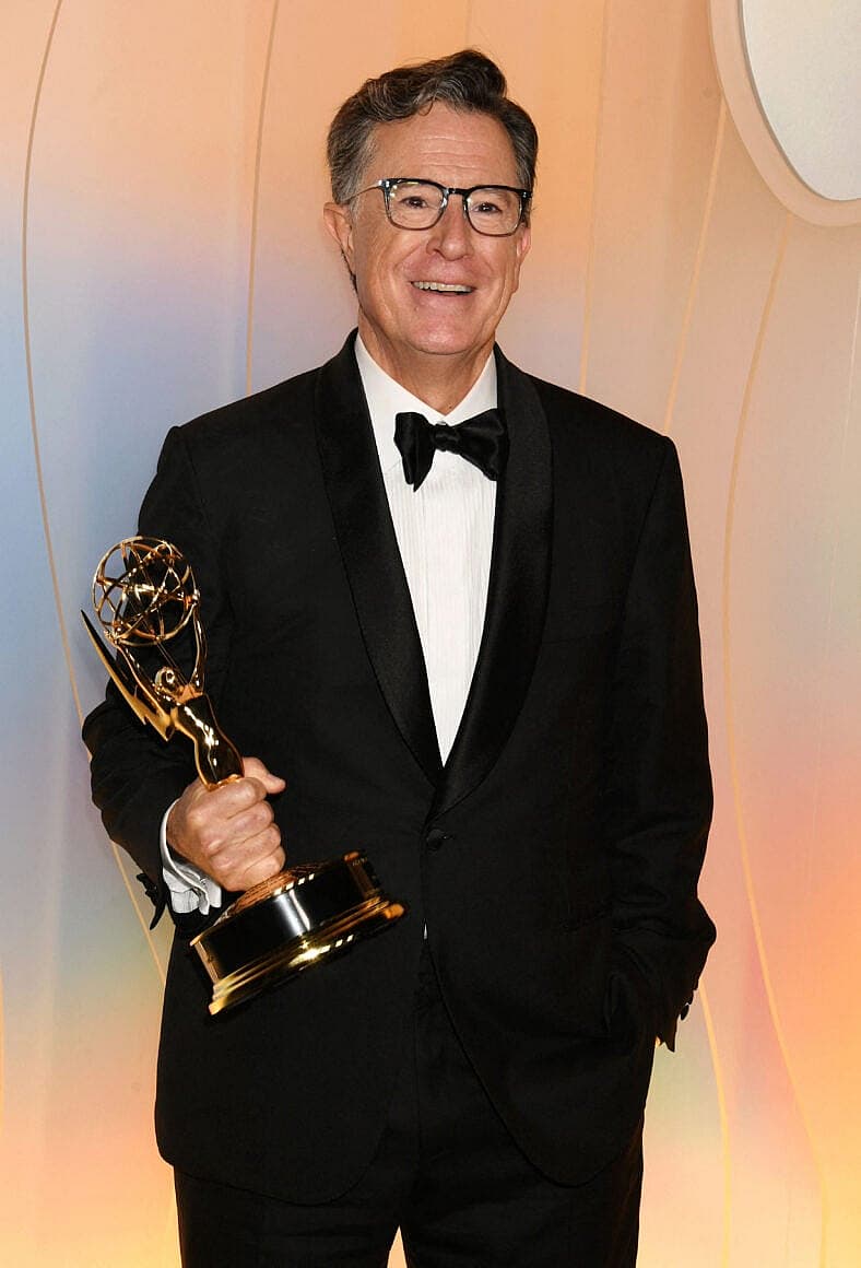Stephen Colbert posing with an Emmy on the red carpet.