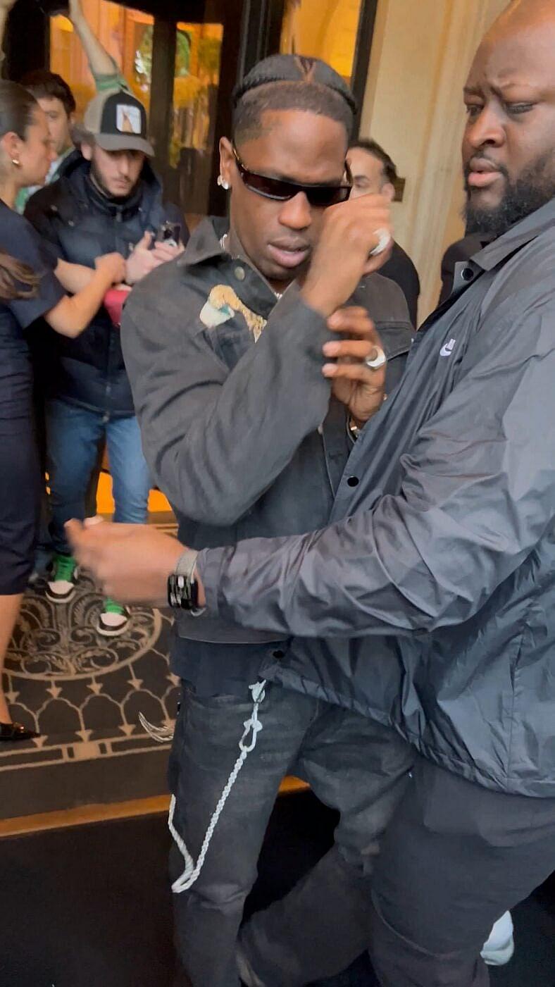 Travis Scott checks to see if his jewelry was taken after being greeted by very excited fans as he returns to his hotel