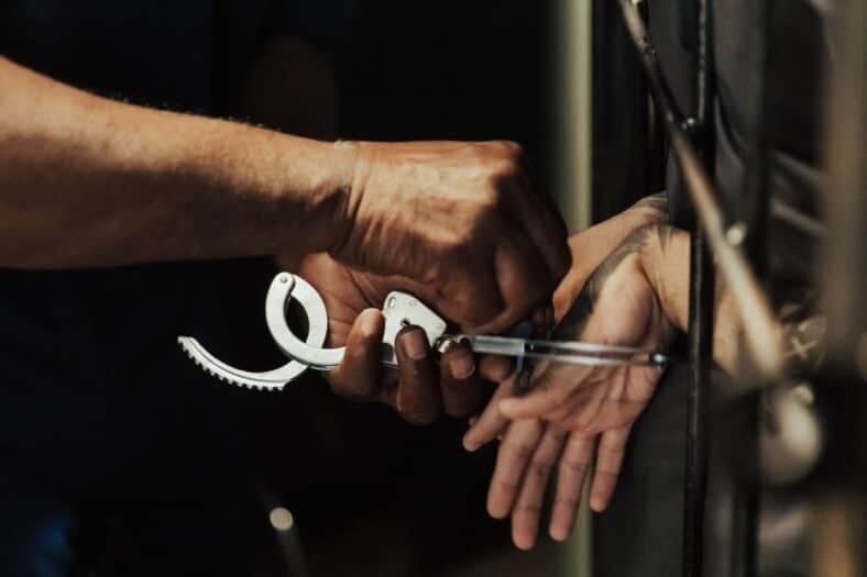 Close-up view of a person being handcuffed in a jail setting
