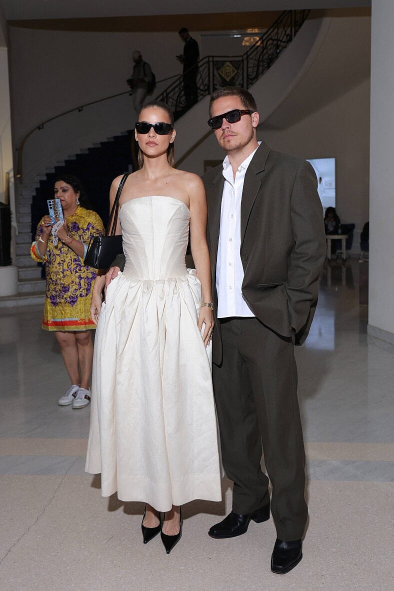 Dylan Sprouse posing on the red carpet with his wife.