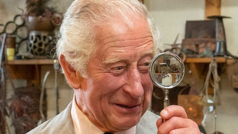 Prince Charles holds up a magnifying glass