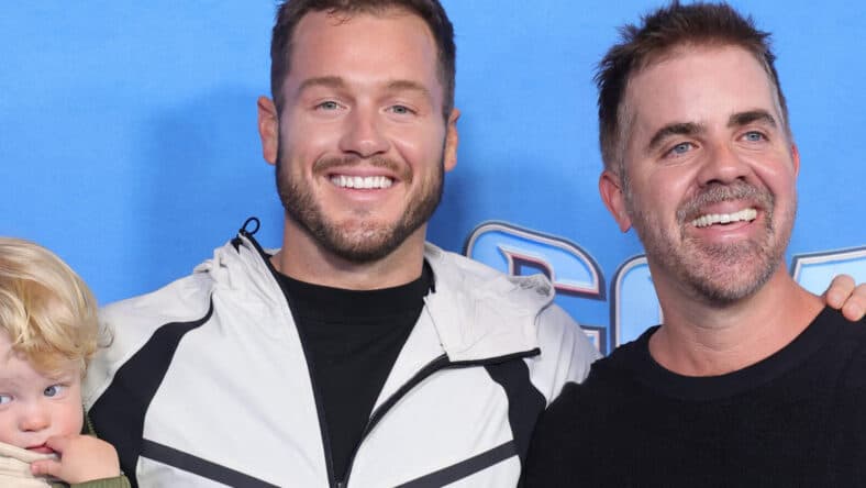 Colton Underwood posing on the red carpet with his husband and their son.