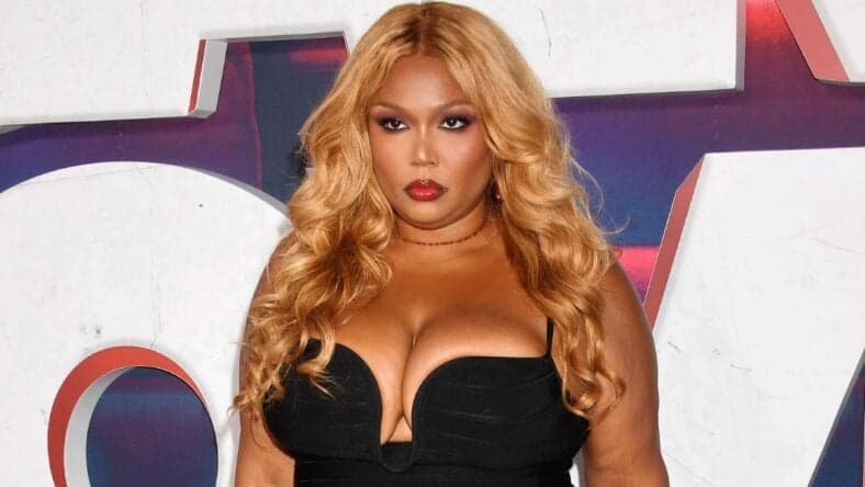 Lizzo posing in a black dress