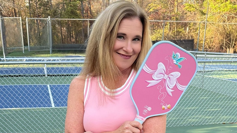 Woman wearing pink and holding a pickleball racket.