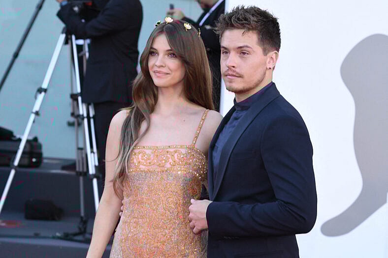 Dylan Sprouse posing on the red carpet with his wife. 