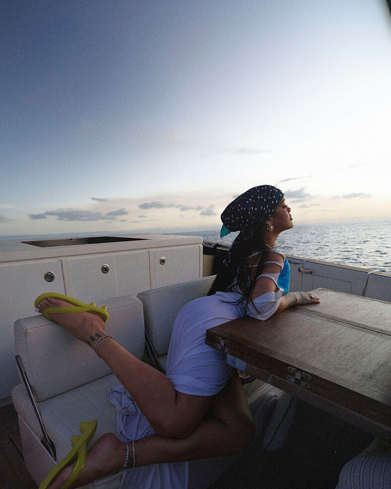 Rihanna puts her feet up on a boat in PUMA Cat Cleat Jelly sandals during her FENTY x PUMA launch celebration in Barbados on March 13