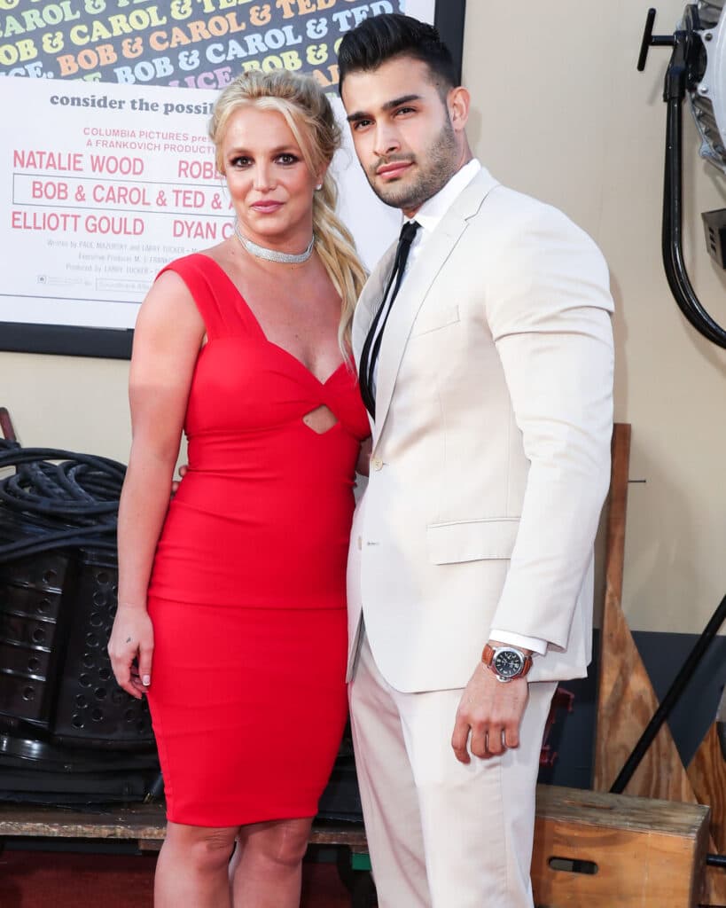 Woman in red dress and man in cream suit pose together at event