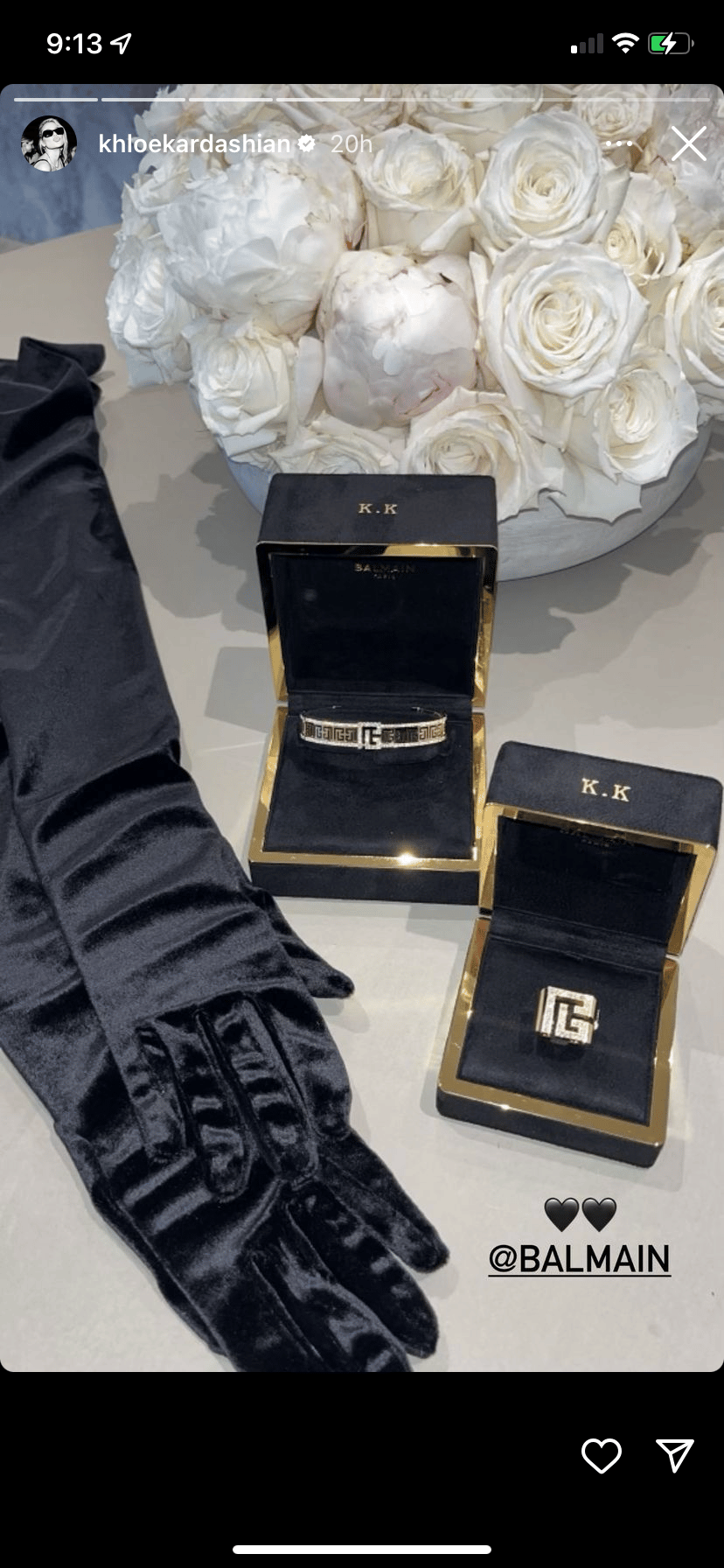 Luxury jewelry boxes with "K.K" initials next to white roses and black gloves