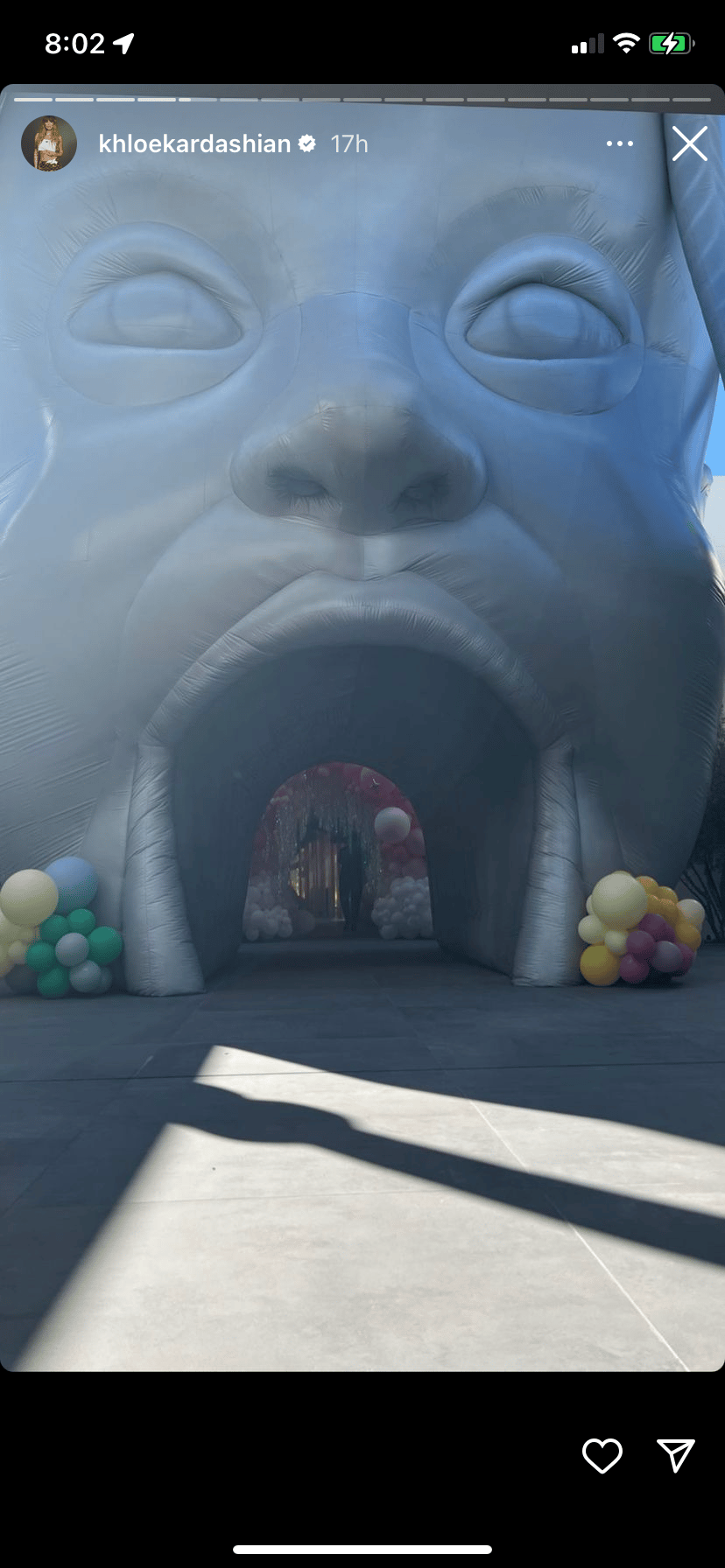 Large inflatable face structure with open mouth entrance and colorful balloons at base