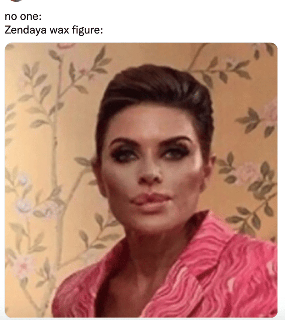 Wax figure with styled dark hair wearing a pink textured jacket against a beige floral wallpaper