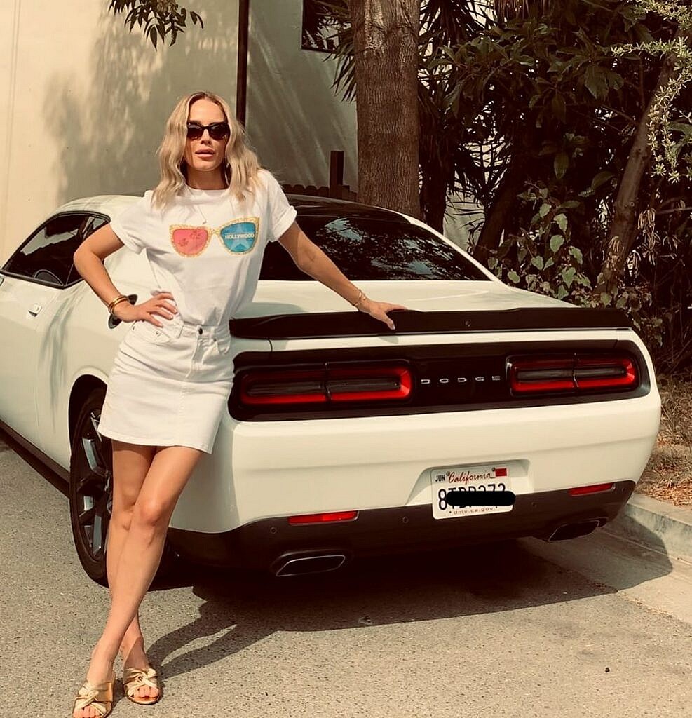 A photo showing Monet Mazur in a skimpy white dress beside a stylish car.