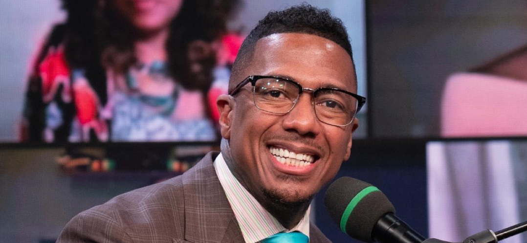 Nick Cannon smiling at a piano