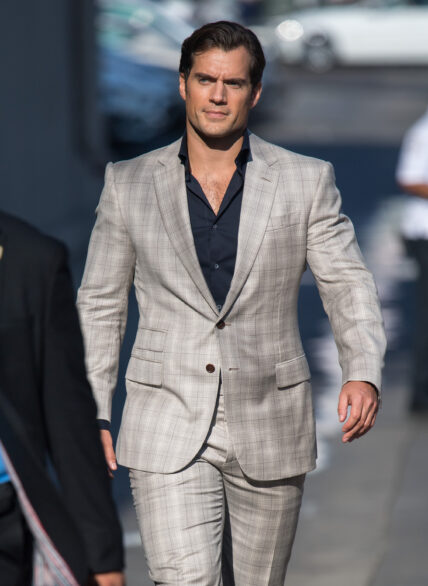 Henry Cavill at 'Kimmel' sporting a gray striped suit and pant paired with a black inner T-shirt.