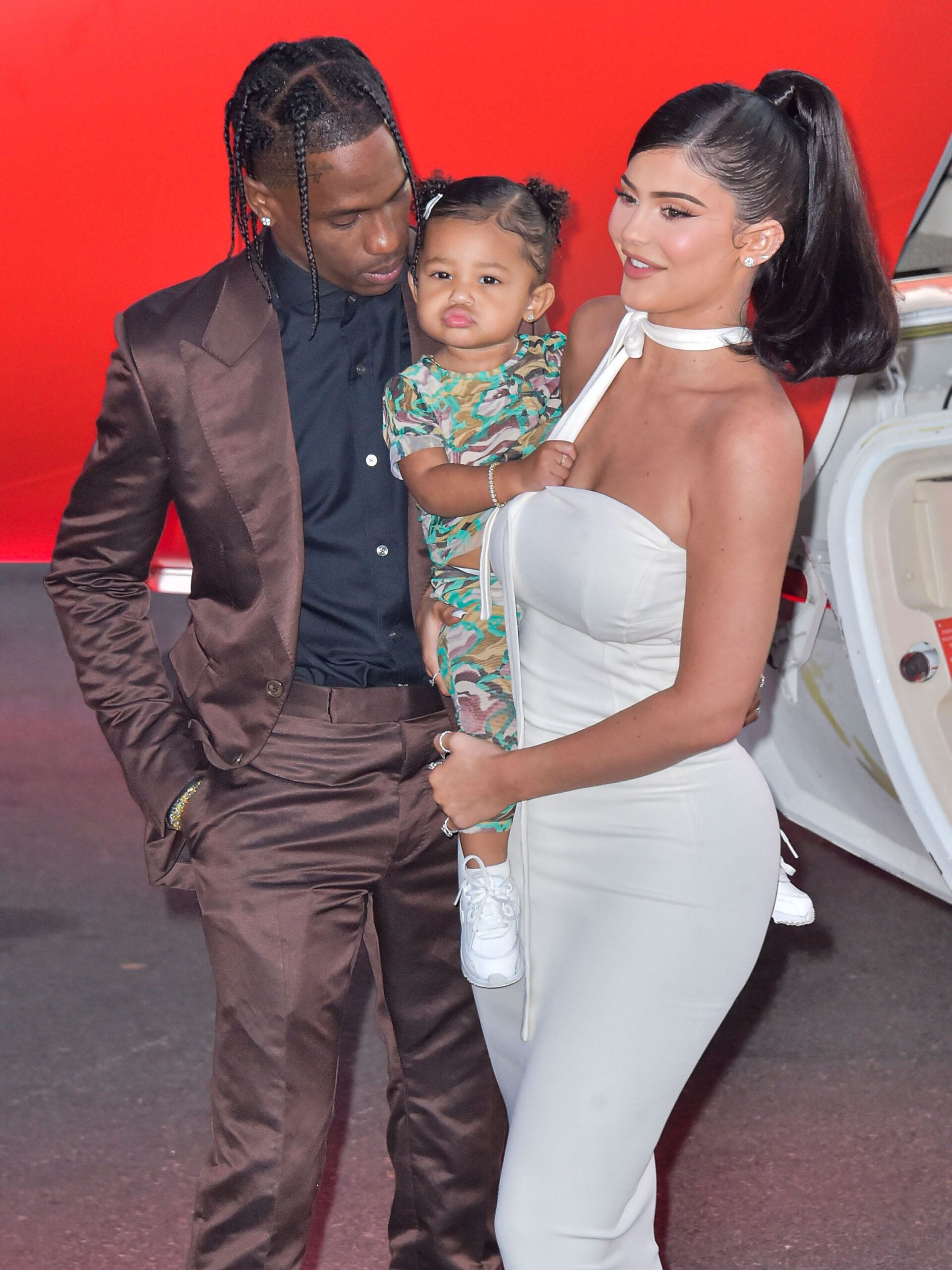 Travis Scott, Stormi Webster, and Kylie Jenner posing for the camera.