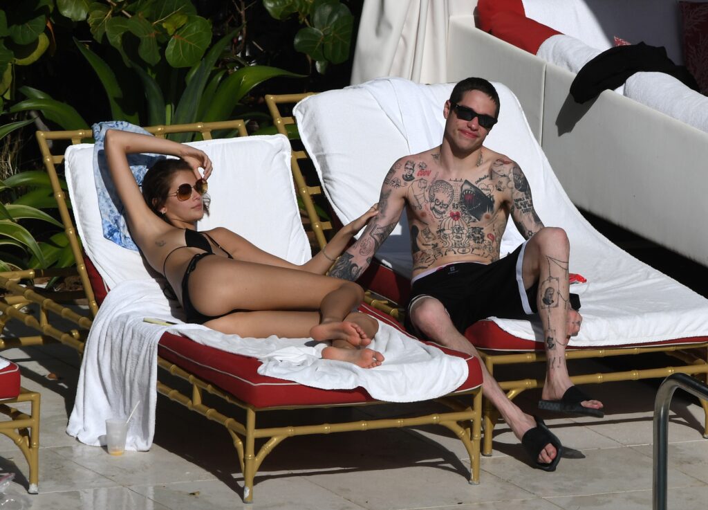 Pete Davidson helps dry off and warm up girlfriend Kaia Gerber as she emerges from the pool in a black bikini in Miami