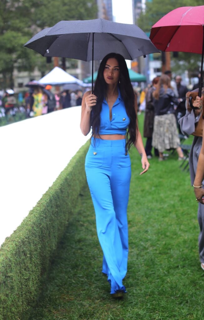 Megan Fox stuns in blue as she stares into the cameras while holding an umbrella in the rain during the Moschino fashion show held outside during fashion week in NYC