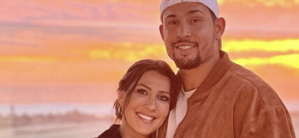 Becca Kufrin and Thomas Jacobs pose in front of the sunset