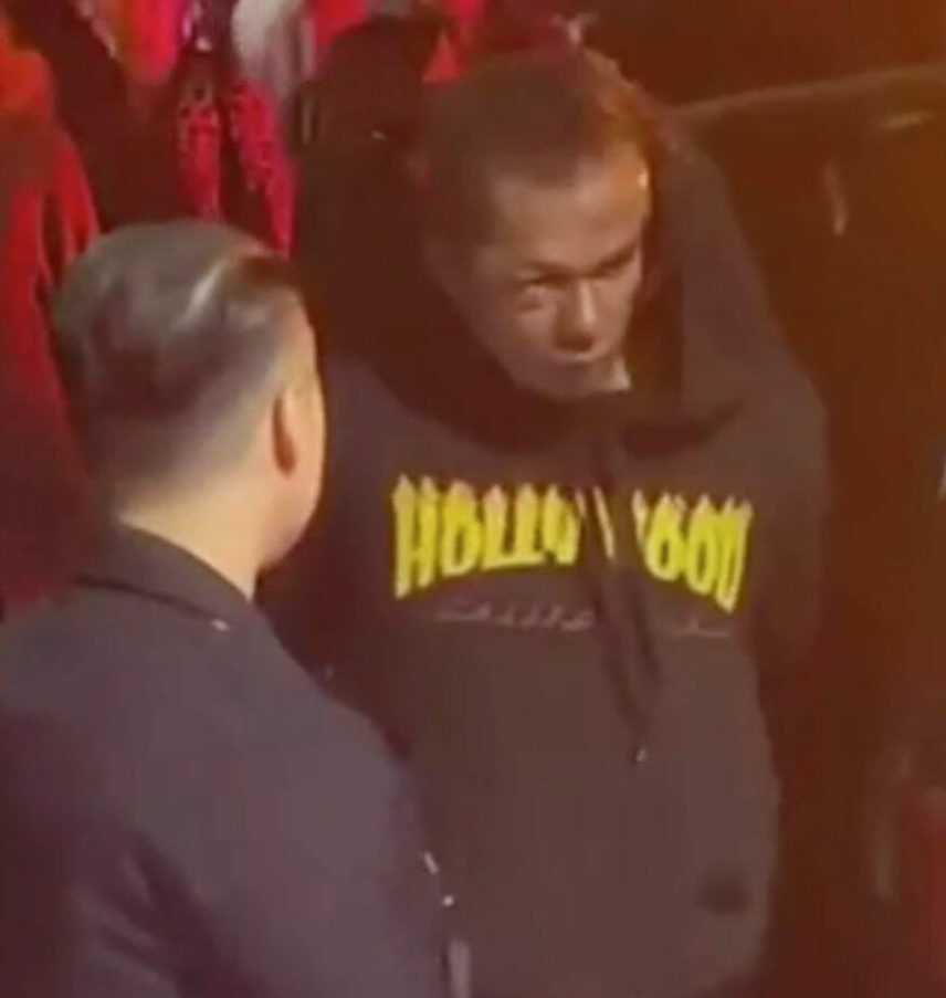 Dave Chappelle s attacker Isaiah Lee with injuries to his face as he is led in handcuffs from a police car to an ambulance
