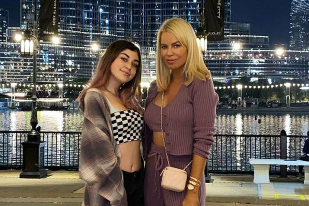 woman and young girl posing in front of water at night