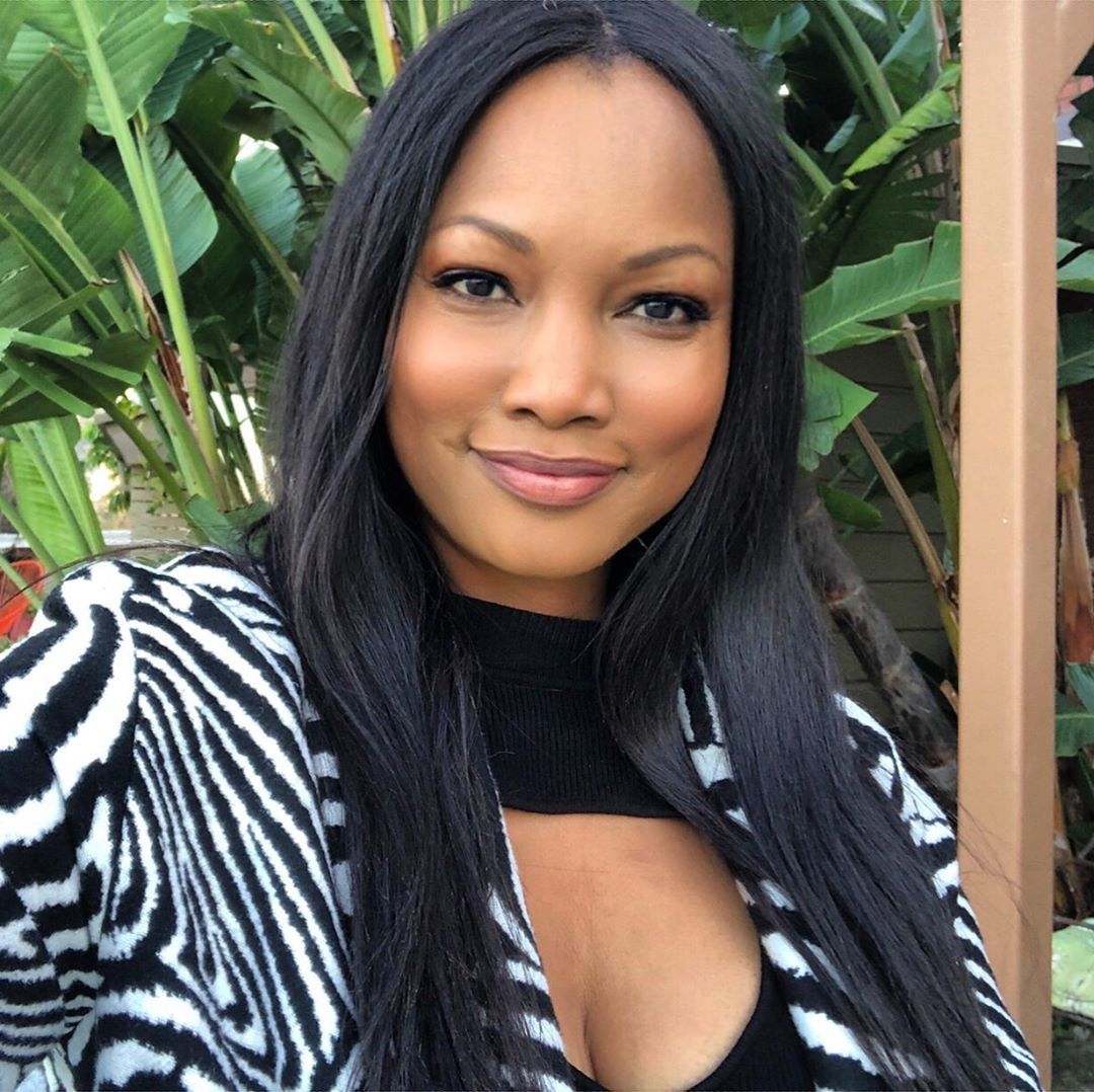 Garcelle Beauvais smiling with plants in the background