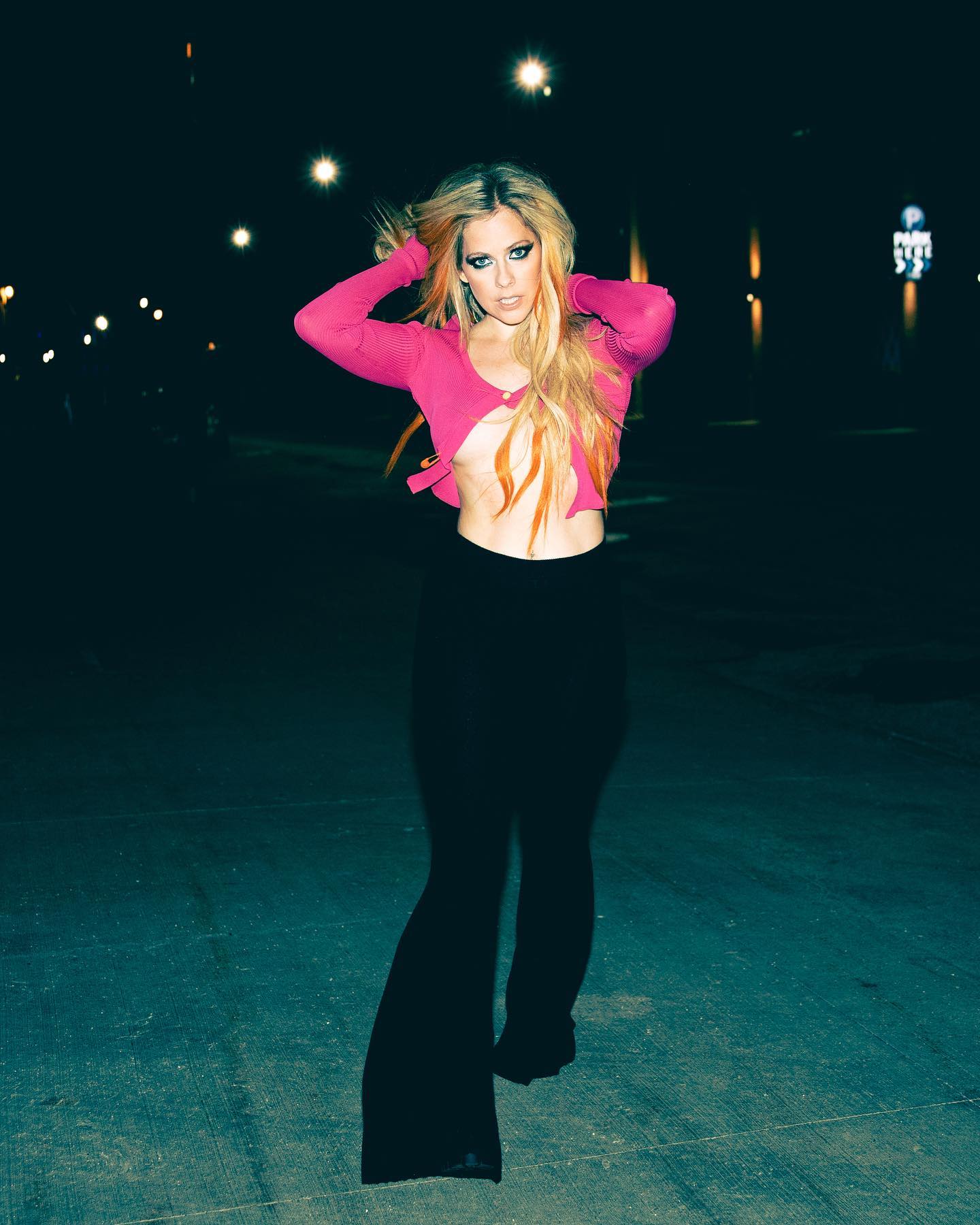 Avril Lavigne in black slacks and a skimpy pink top