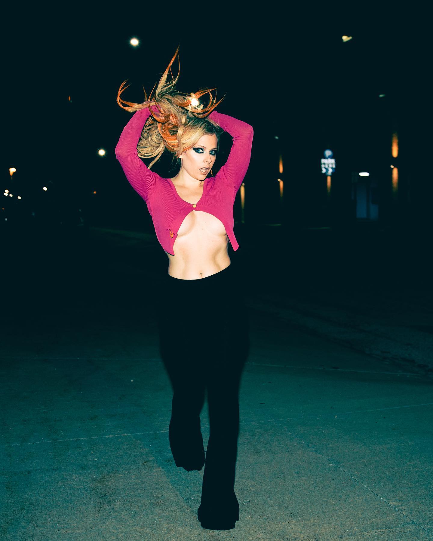 Avril Lavigne in black slacks and a skimpy pink top