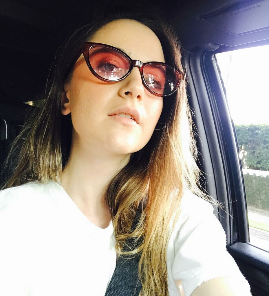 Alexa Nikolas taking a selfie in a car with sunglasses on