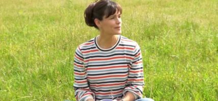 Jennifer Garner sitting in a field wearing red Hunter boots.