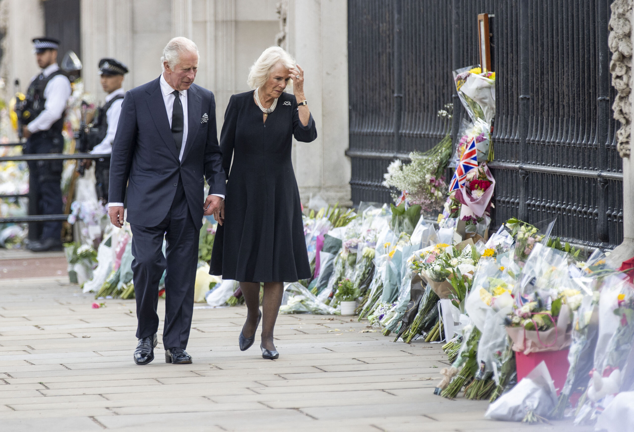 King Charles III and Queen Consort Camilla look at floral tributes left for Queen Elizabeth II outside Buckingham Palace in central London