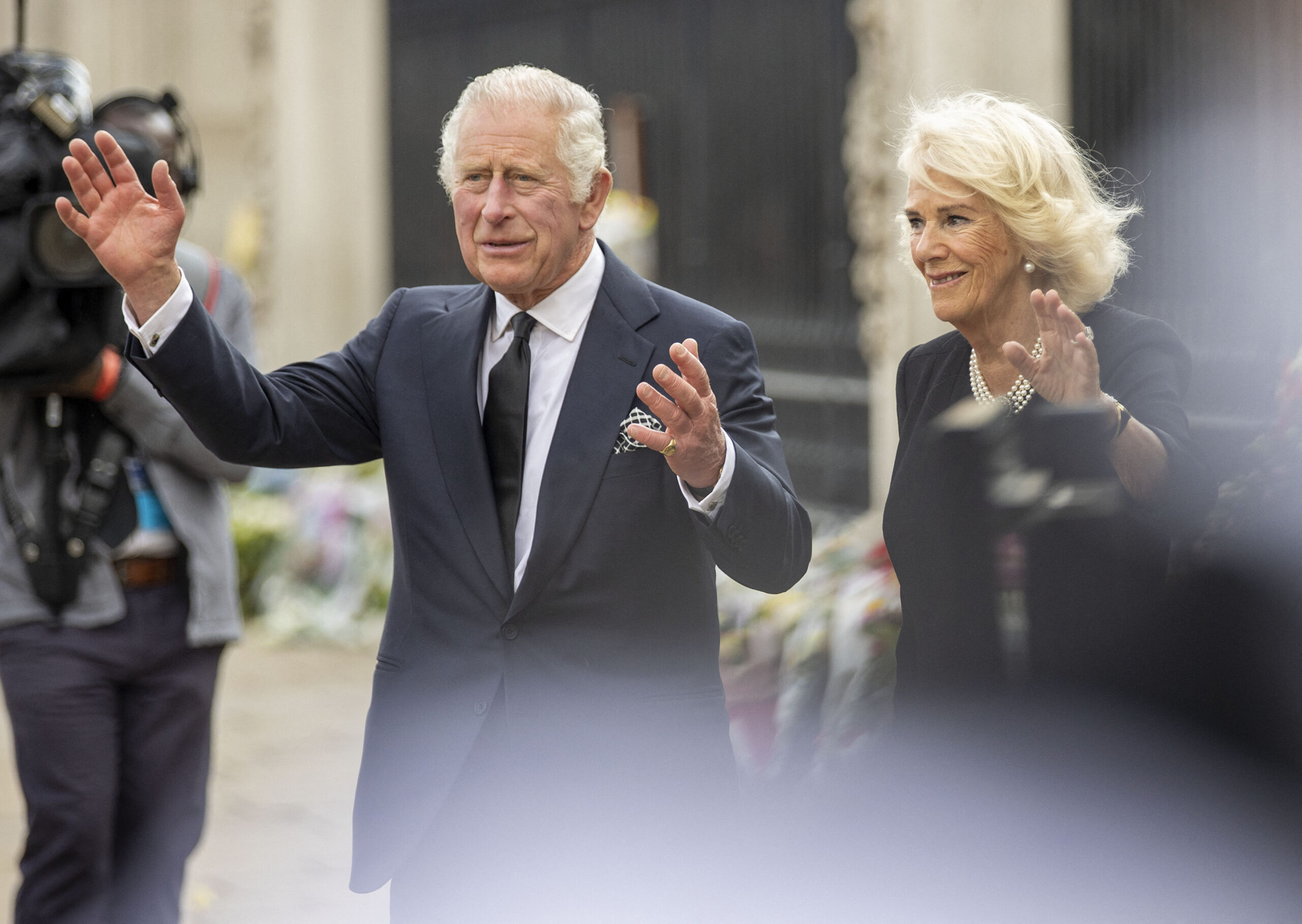 King Charles III and Queen Consort Camilla look at floral tributes left for Queen Elizabeth II outside Buckingham Palace in central London