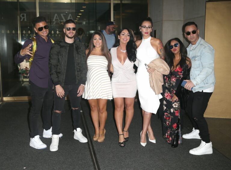 Group of eight people posing together indoors at what appears to be a media event