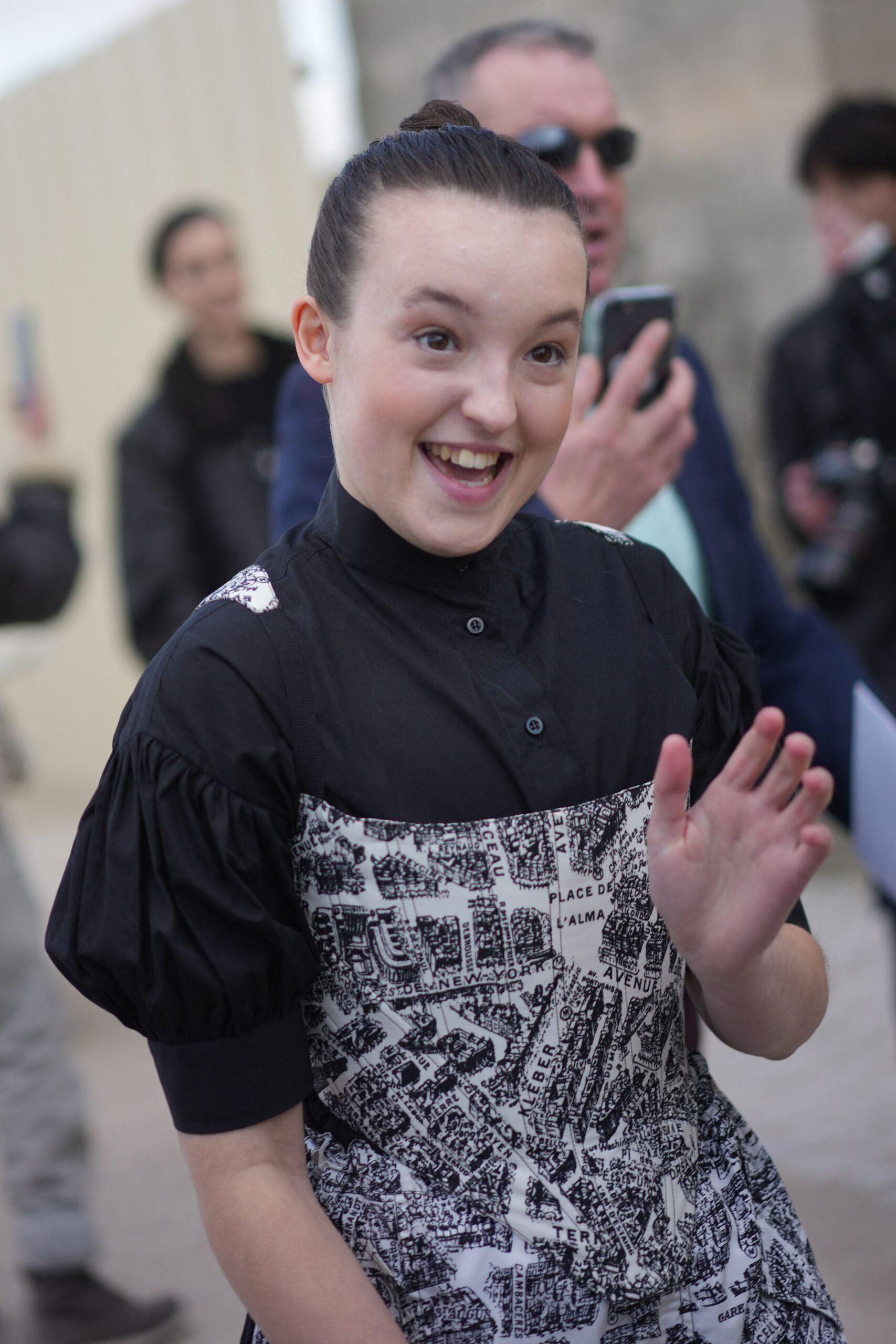 Bella Ramsey Greets Fans at Exit Of Paris Dior Show in Print Overalls Look