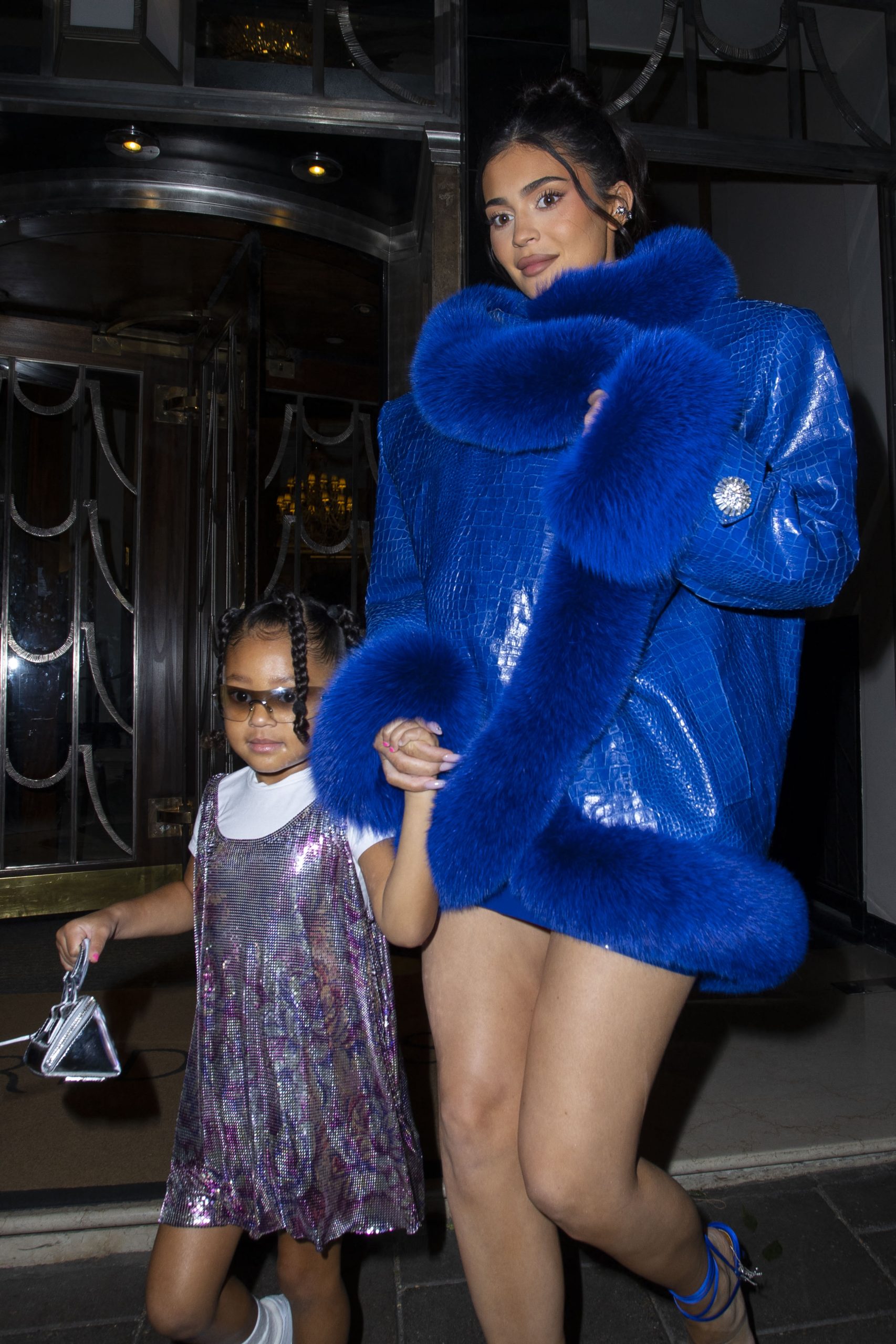 Kylie Jenner and daughter Stormi wow fans as they leave their hotel wearing an oversized blue crocodile skin and fur coat, with a very leggy display
