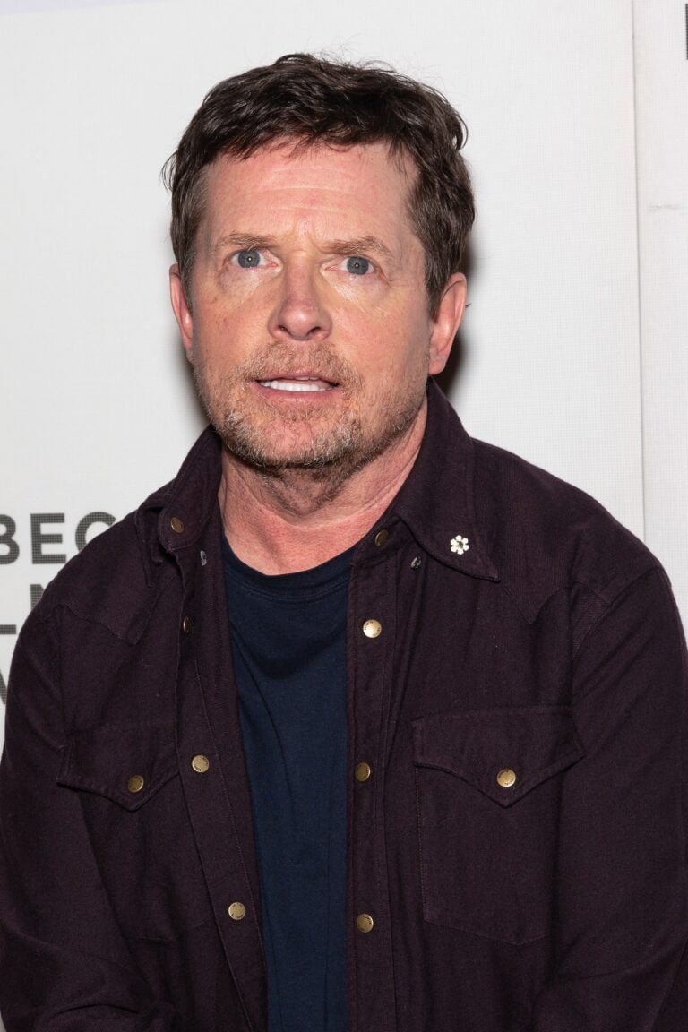 Michael J. Fox at a media event wearing a dark jacket over a navy shirt
