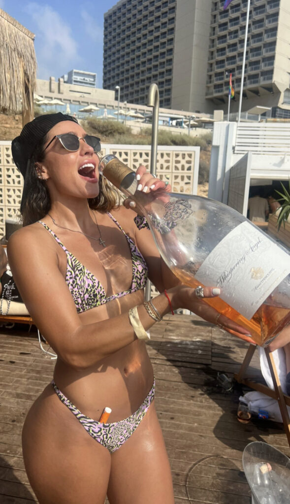 Sommer Ray holding a big bottle of wine while wearing a tiny bikini.