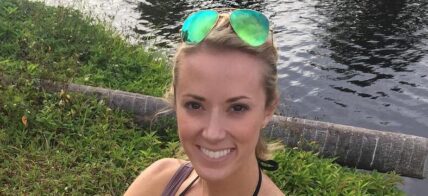 Vicky Stark in a brown tank top and blue shorts poses for the camera while showing off the fish she caught.