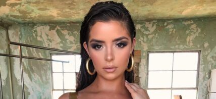 Demi Rose poses for the camera in a gold one-piece.