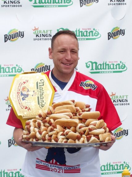 Joey Chestnut holding a plate of hot dogs at Nathan's July 4th Hot Dog Eating Contest 2021