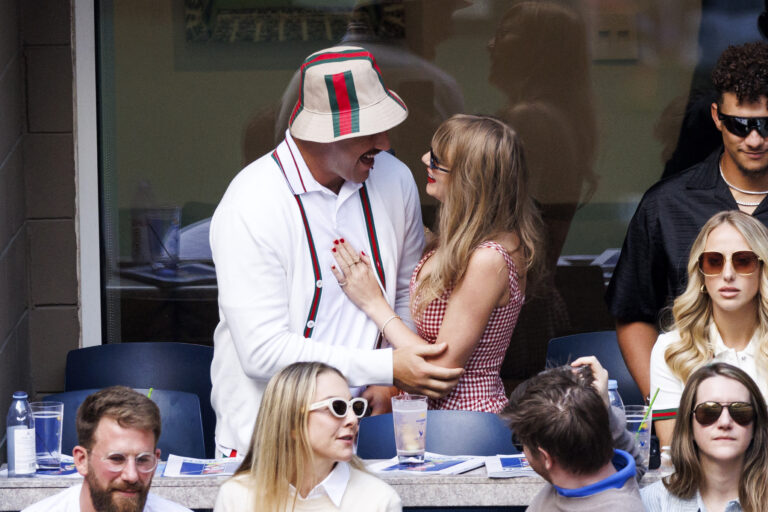 Travis Kelce and Taylor Swift interact while seated at a sporting event