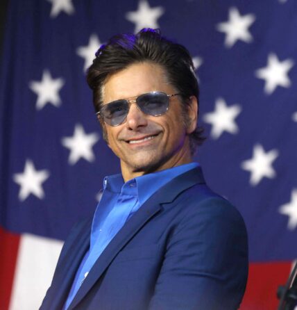 John Stamos stands in front of American flag