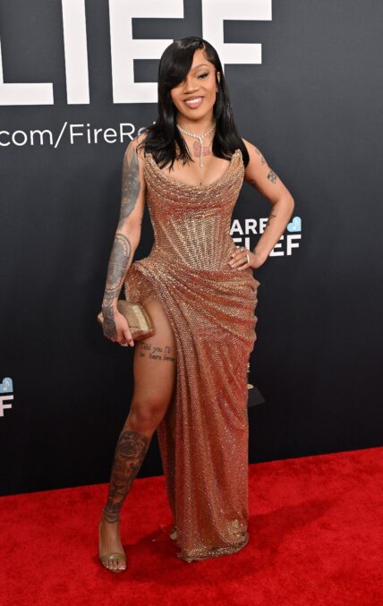 Glorilla posing on the red carpet in a gold dress during the Grammys.