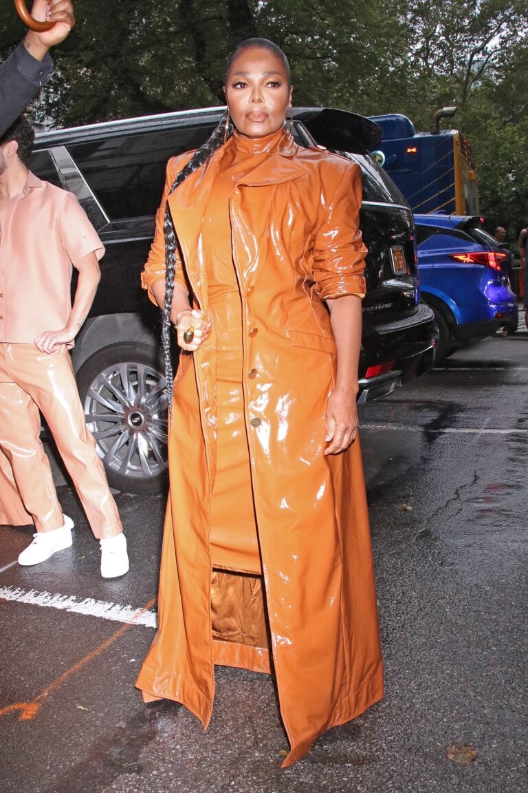 Janet Jackson in orange patent trench coat arriving at event